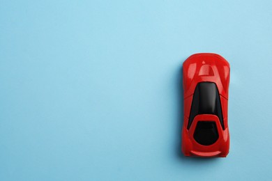 Photo of One red car on light blue background, top view with space for text. Children`s toy