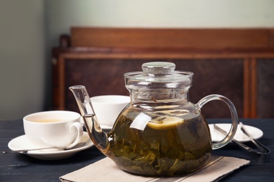 Teapot with hot aromatic tea on table