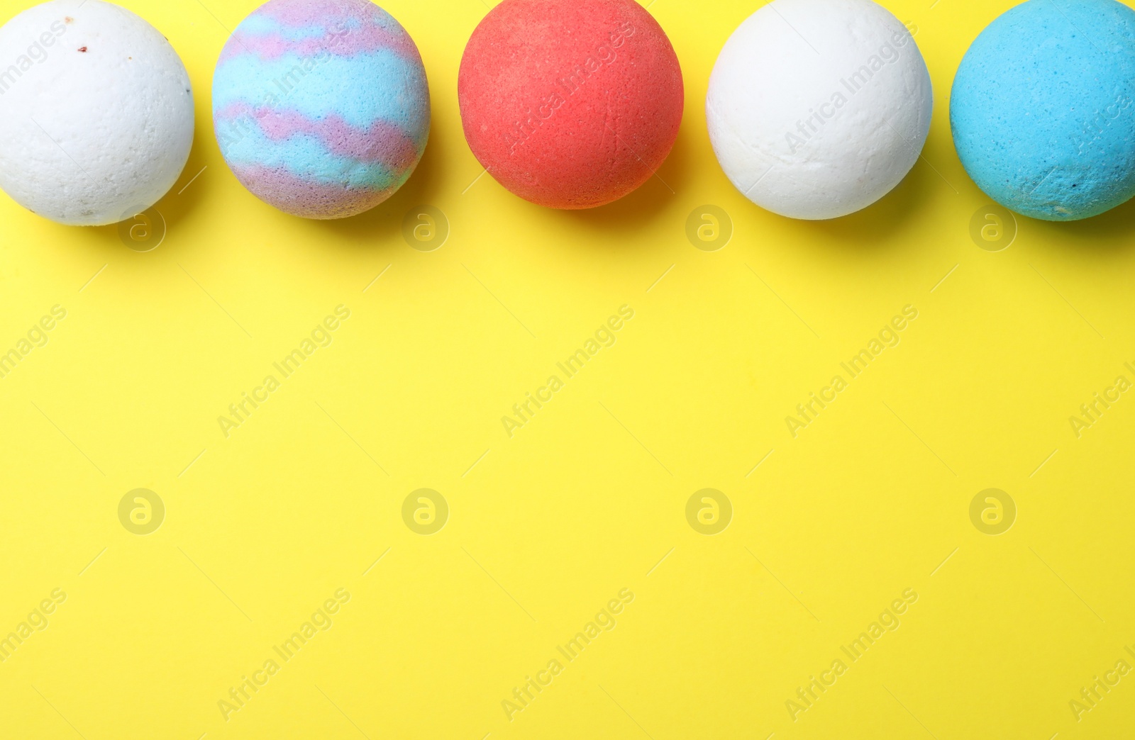 Photo of Colorful bath bombs on yellow background, flat lay. Space for text