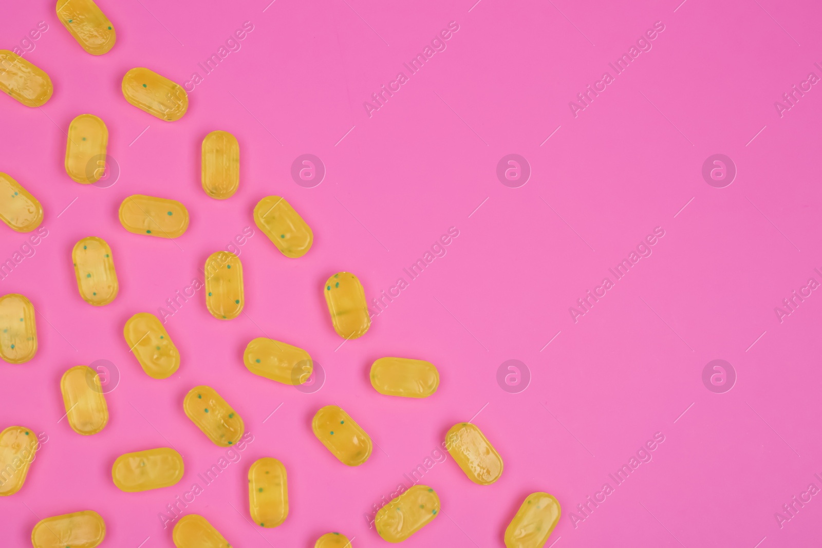 Photo of Many delicious lemon drops on pink background, flat lay. Space for text