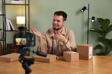 Smiling blogger with many parcels recording video at home