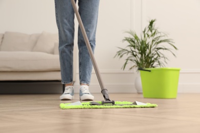 Woman cleaning floor with mop at home, closeup