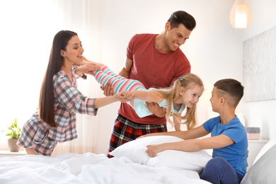 Happy young family with children having fun in bedroom