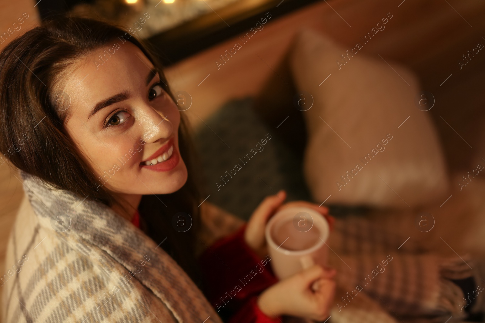 Photo of Young woman with plaid drinking coffee at home. Winter season