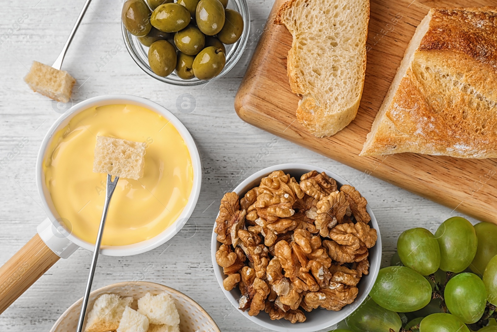 Photo of Flat lay composition with pot of tasty cheese fondue  on white wooden table