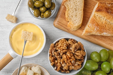 Photo of Flat lay composition with pot of tasty cheese fondue  on white wooden table