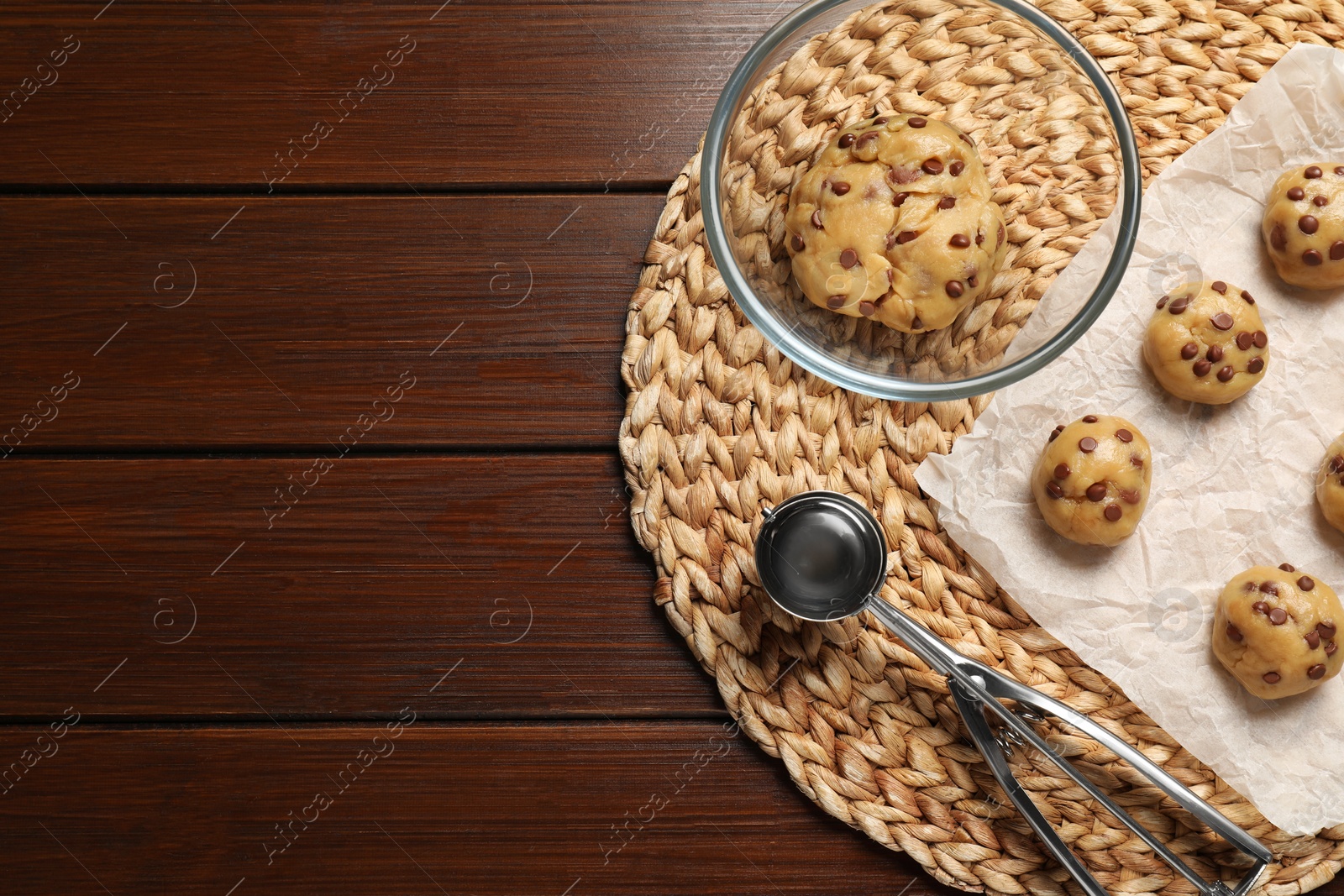 Photo of Fresh dough and uncooked chocolate chip cookies on wooden table, top view. Space for text
