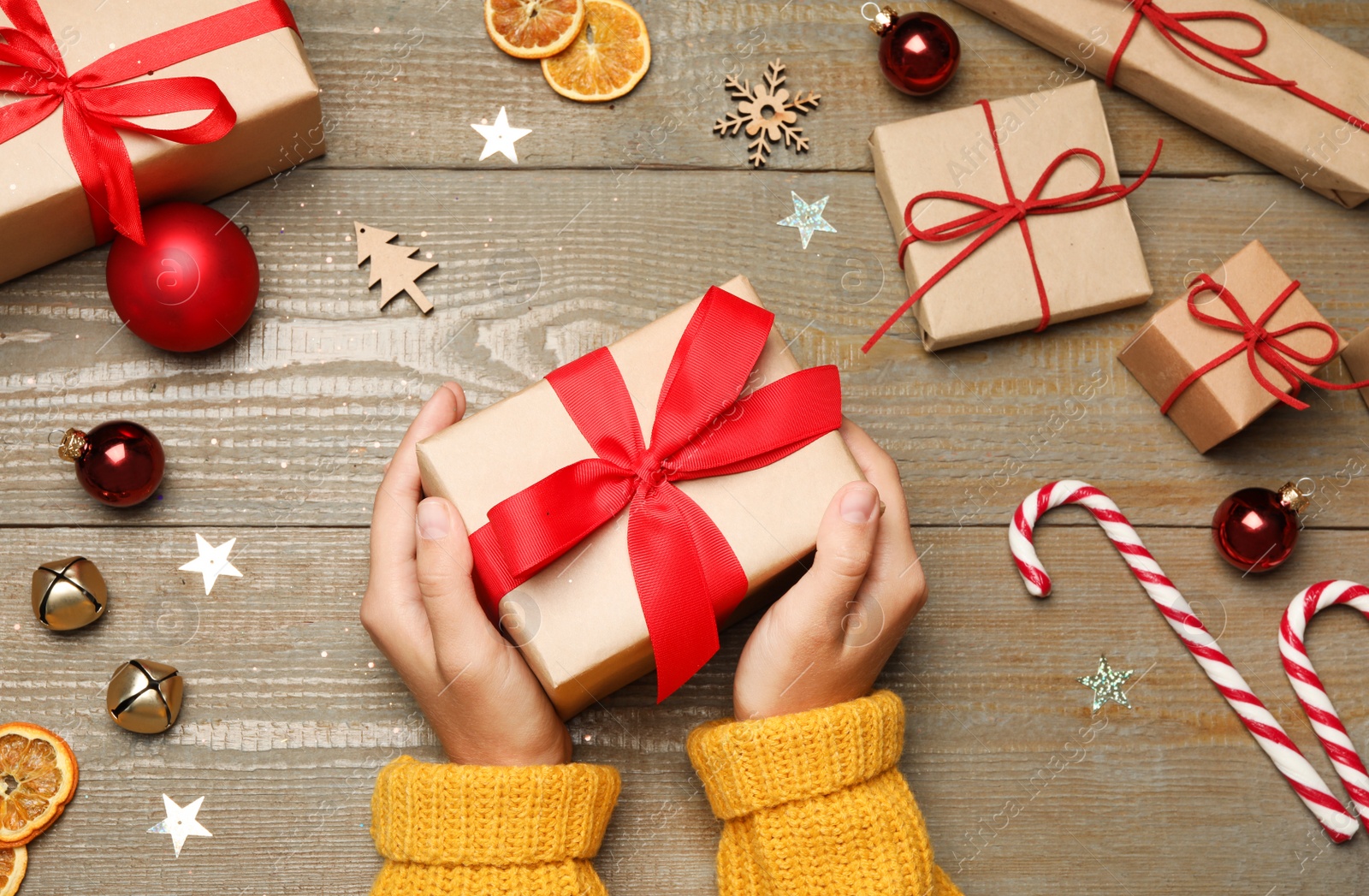 Photo of Young woman holding Christmas gift on wooden background, flat lay