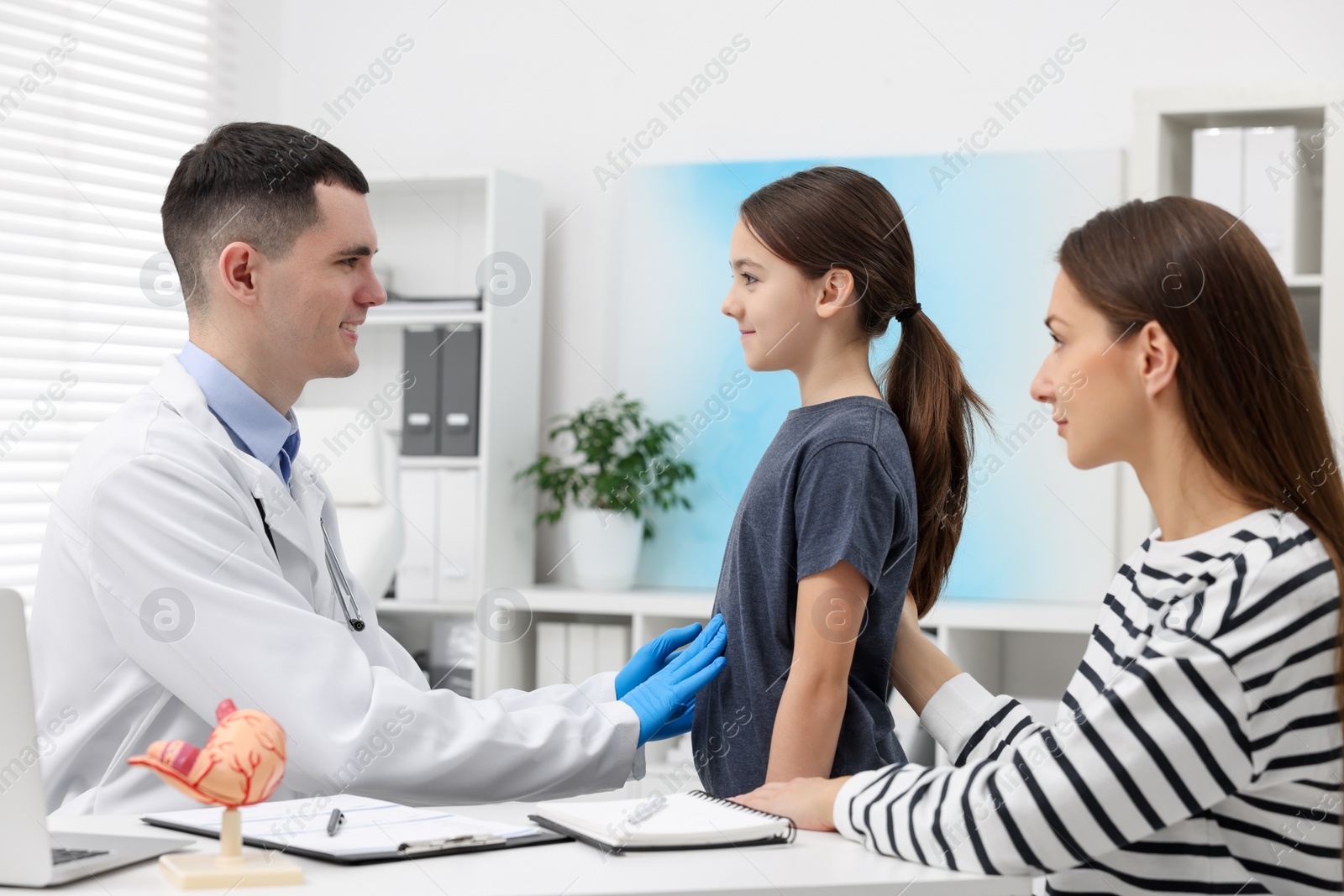 Photo of Gastroenterologist examining girl with stomach ache in clinic