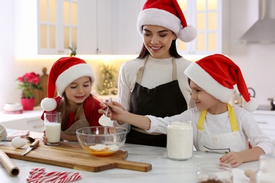 Photo of Mother with her cute little children making Christmas cookies in kitchen
