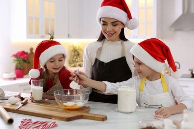 Mother with her cute little children making Christmas cookies in kitchen