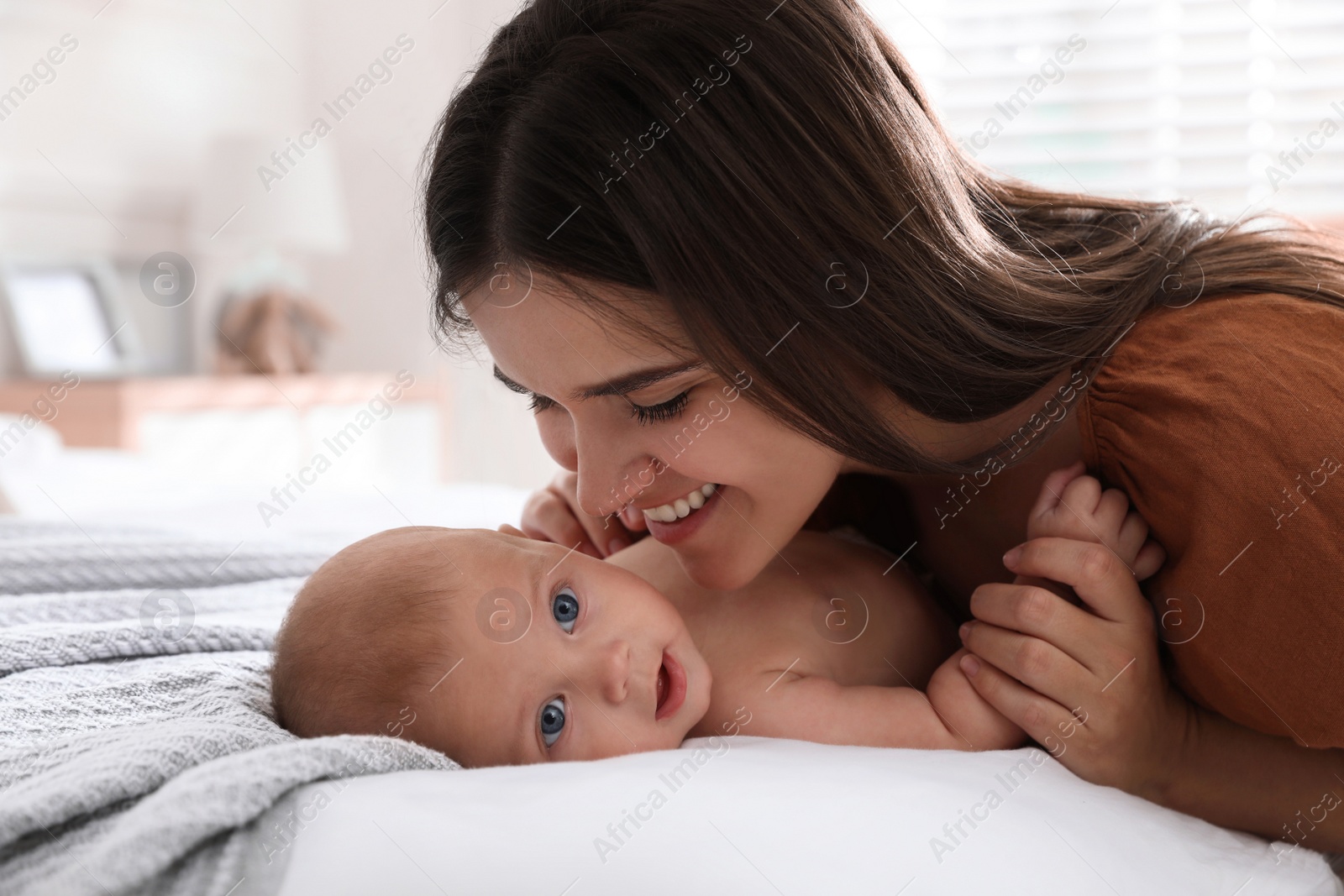 Photo of Mother with her cute baby on bed at home