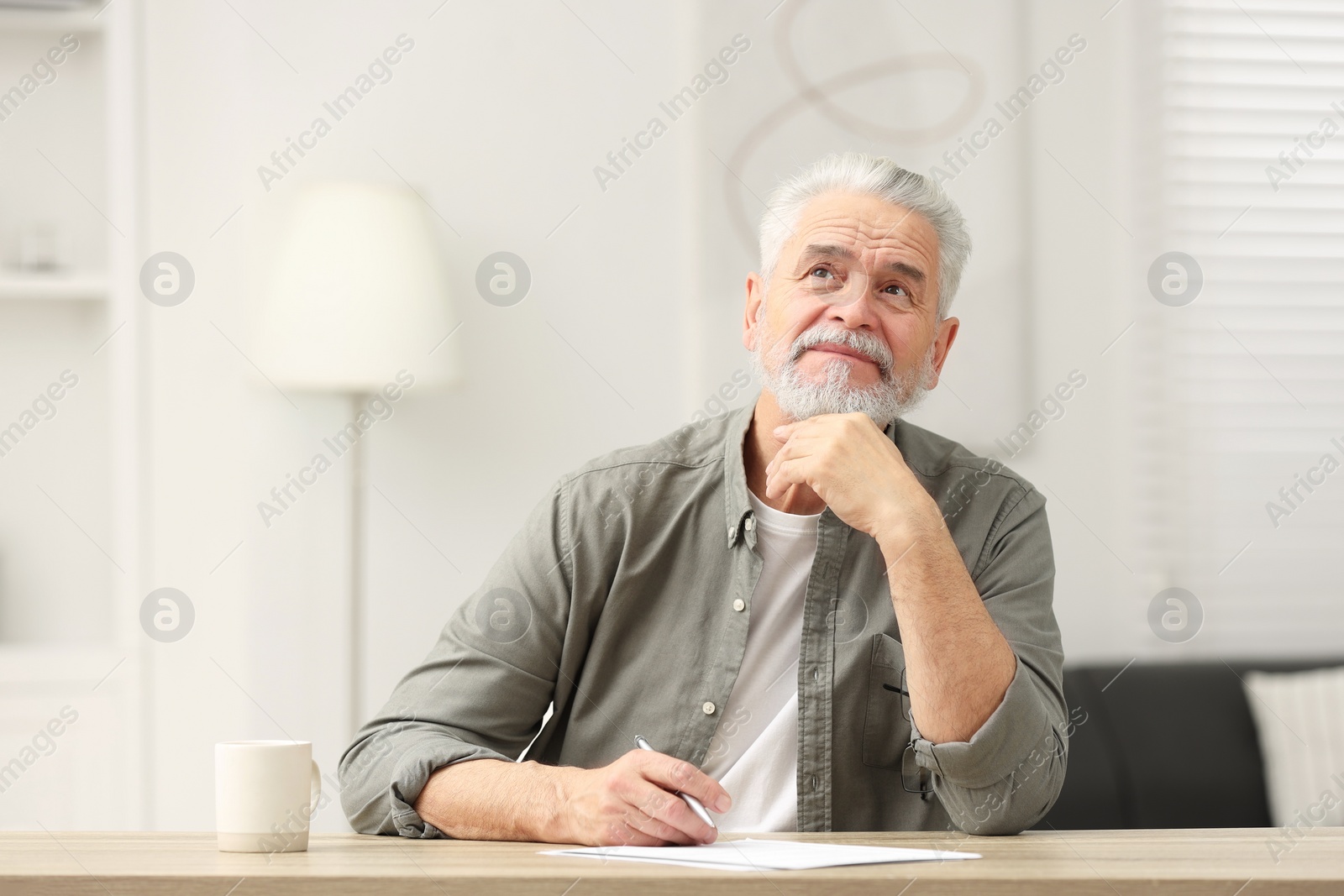 Photo of Senior man signing Last Will and Testament at table indoors. Space for text