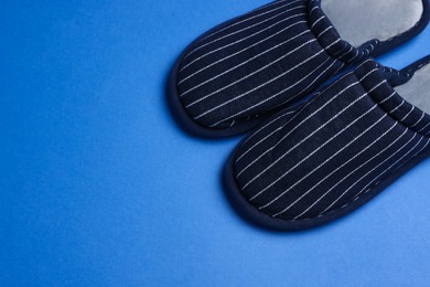 Photo of Pair of stylish slippers on blue background, space for text