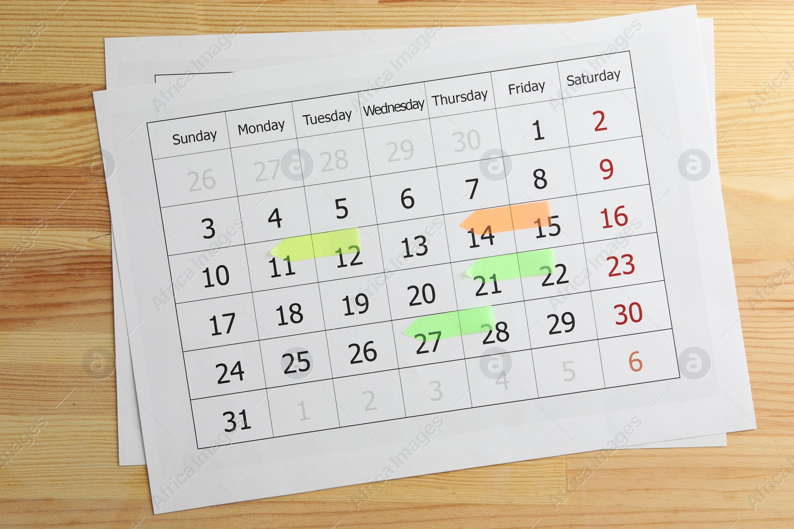 Photo of Timetable. Calendar page with colorful sticky notes on wooden table, top view