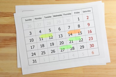 Timetable. Calendar page with colorful sticky notes on wooden table, top view