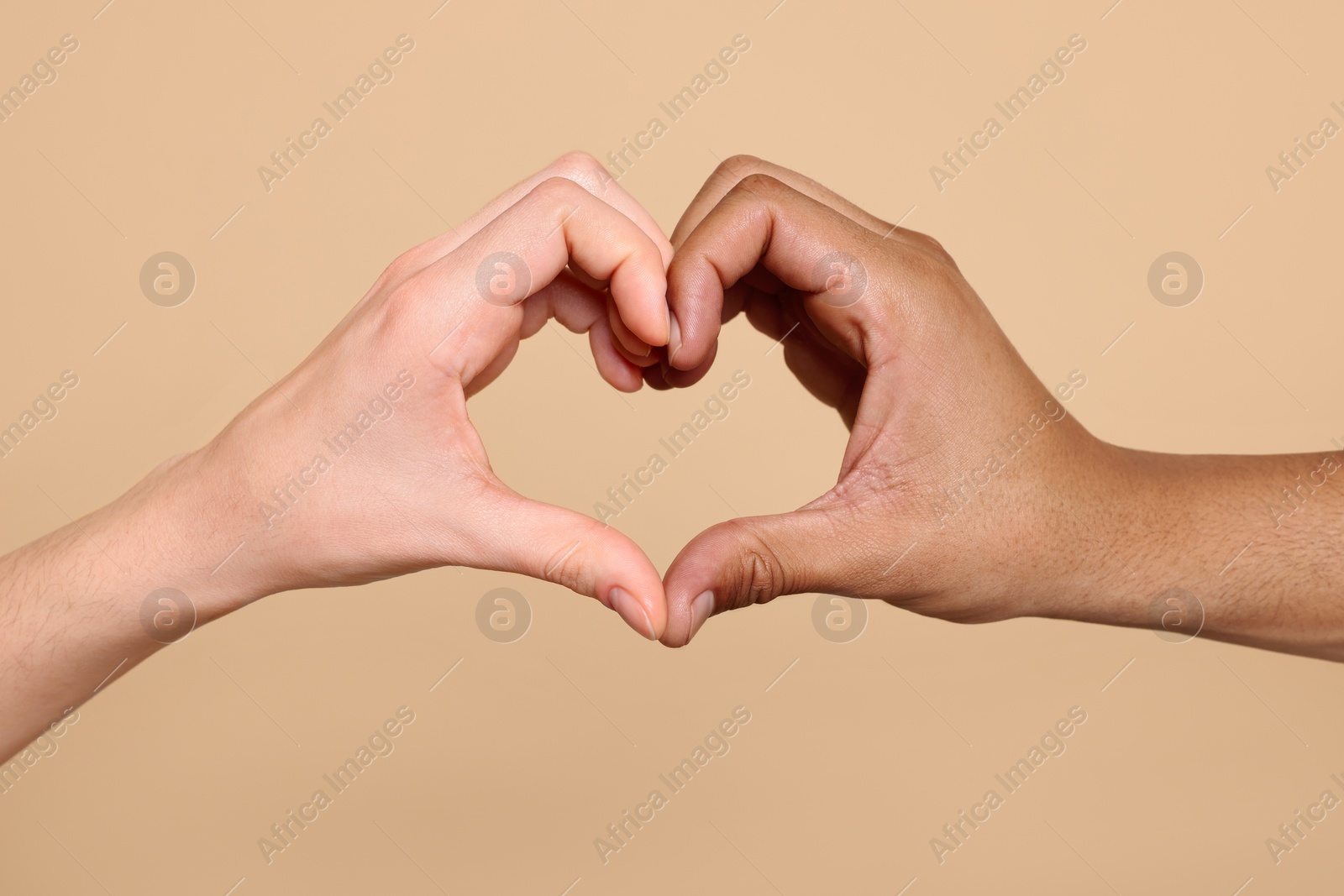 Photo of International relationships. People making heart with hands on light brown background, closeup