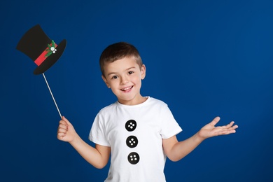 Cute little boy with Christmas hat prop on blue background