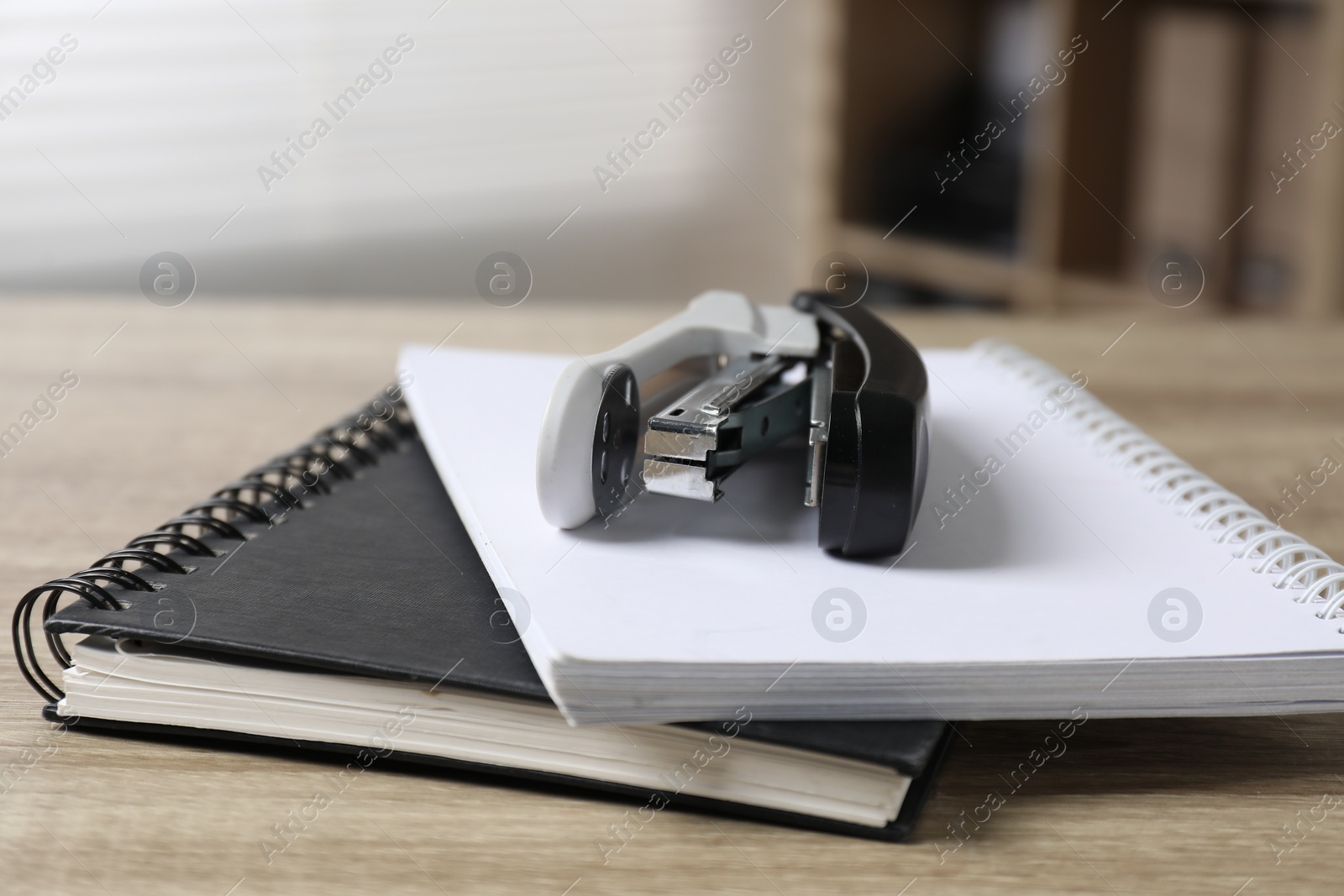 Photo of Stapler and notebooks on wooden table indoors, closeup