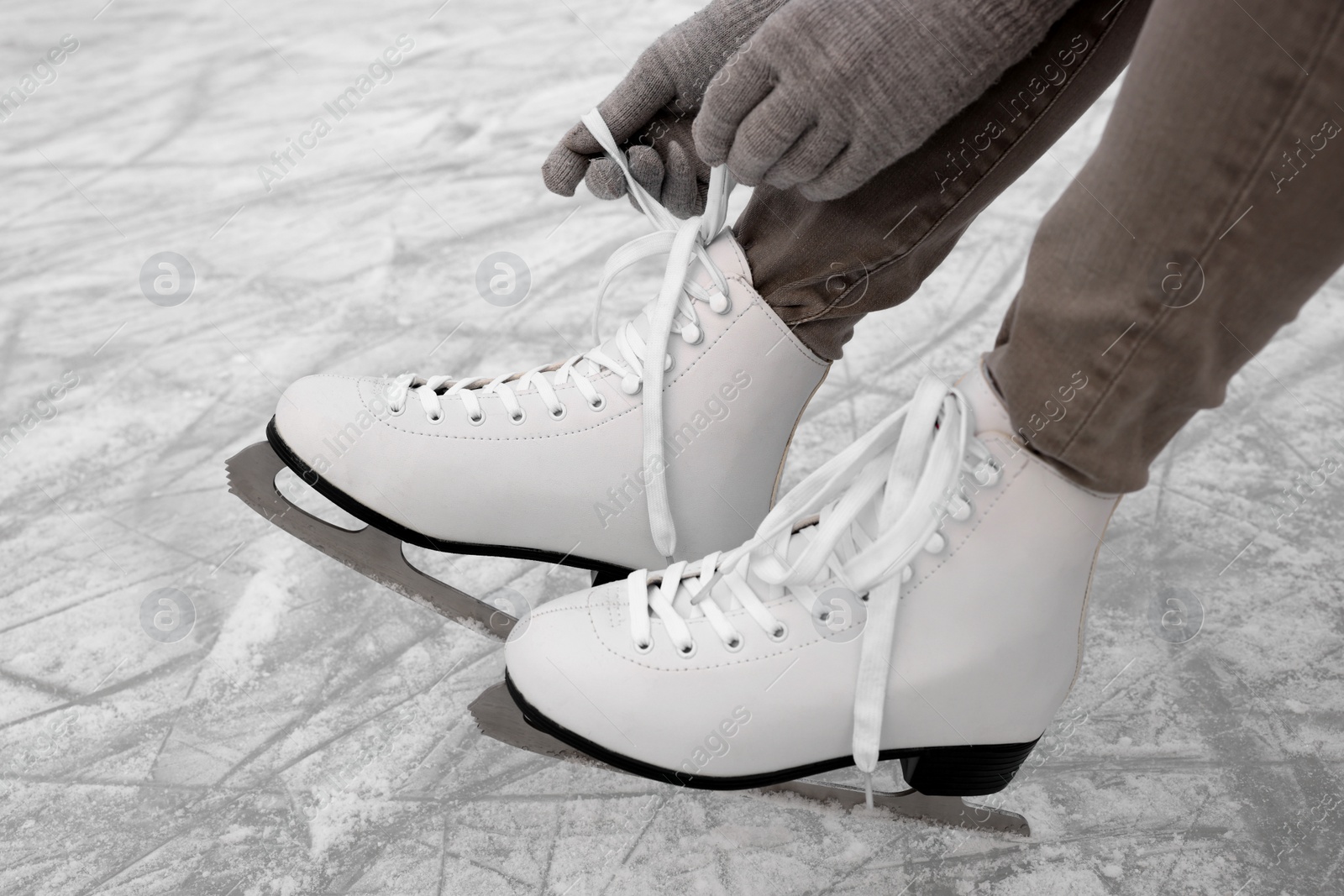 Photo of Woman lacing figure skates on ice, closeup