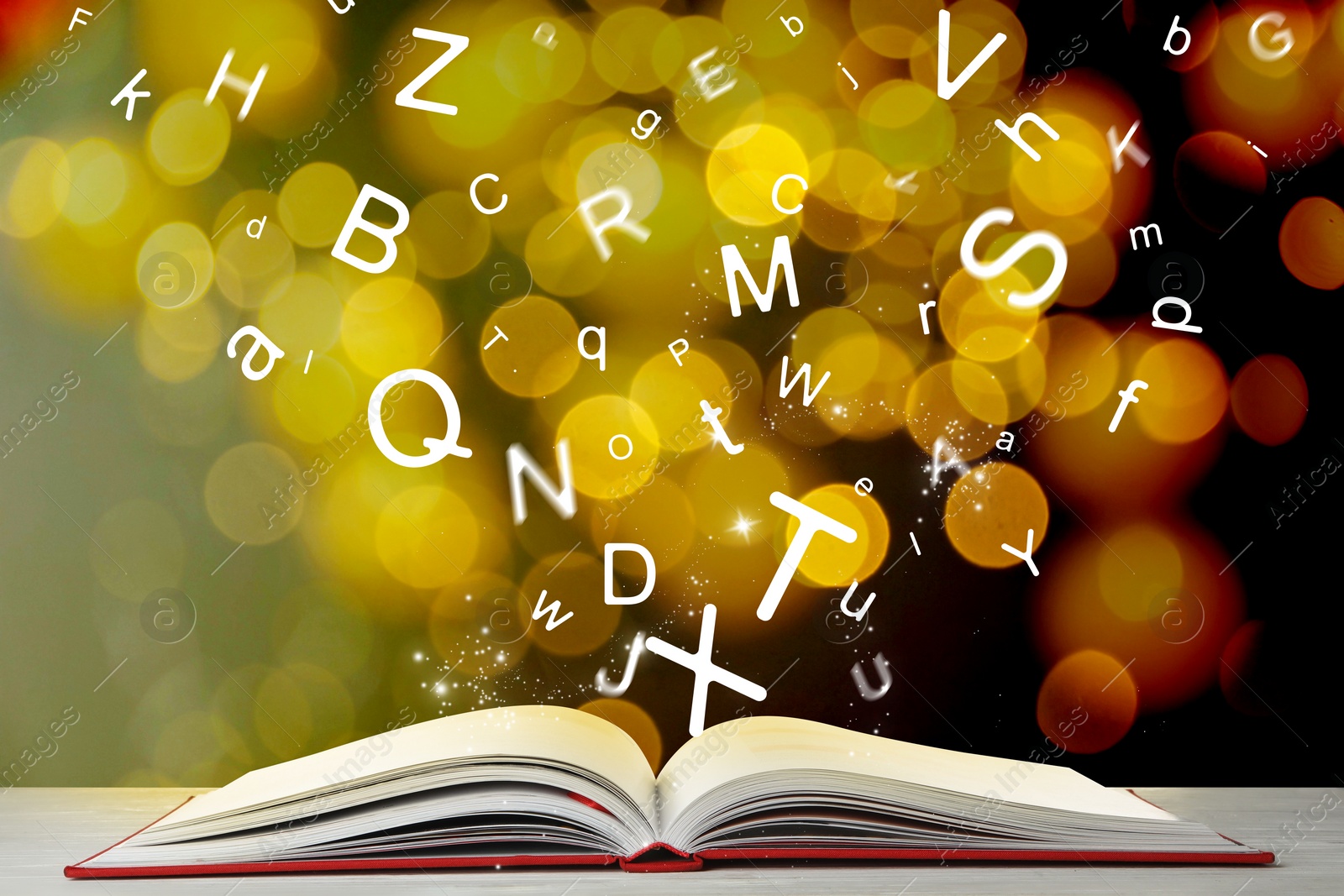 Image of Letters flying out from open book on table, bokeh effect