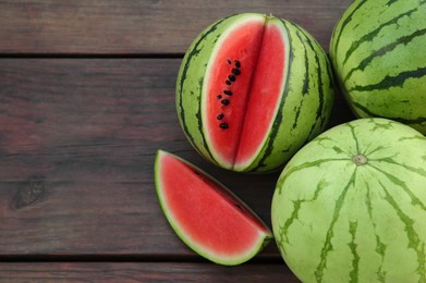 Different delicious ripe watermelons on wooden table, flat lay. Space for text
