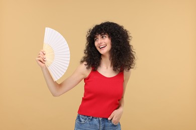 Photo of Happy woman holding hand fan on beige background