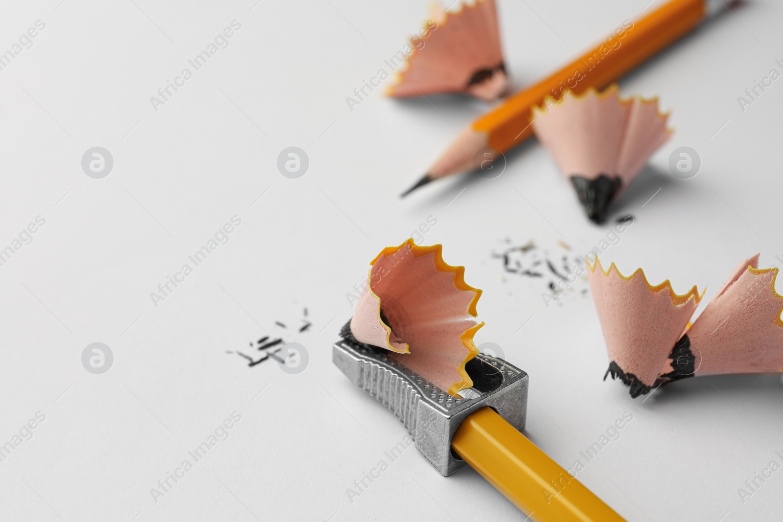 Photo of Graphite pencils, shavings and sharpener on white background, closeup. Space for text