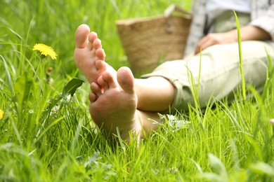 Woman sitting barefoot on green grass outdoors, closeup