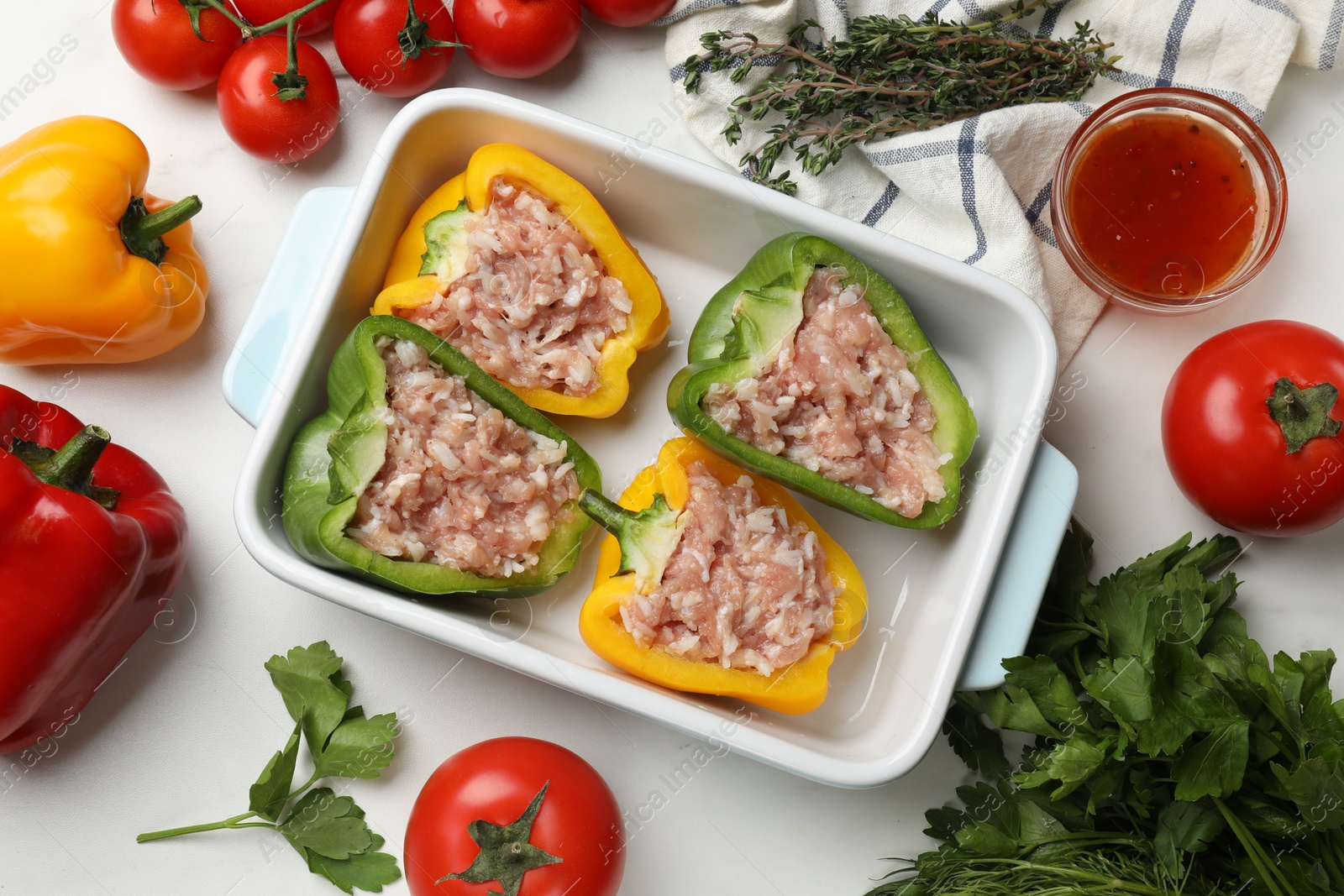 Photo of Raw stuffed peppers and ingredients on white table, flat lay