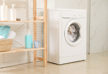 Modern washing machine with towels in bathroom