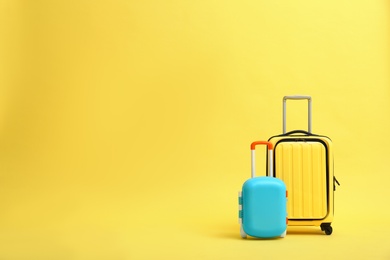 Stylish suitcases on yellow background, space for text