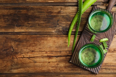 Photo of Fresh aloe drink in glasses on wooden table, flat lay. Space for text