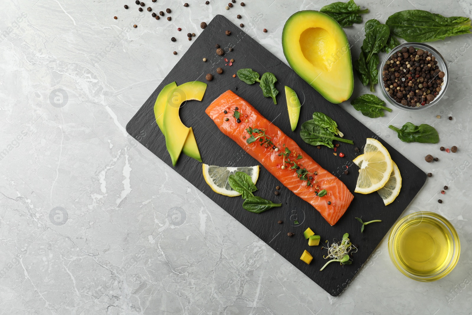 Photo of Delicious fresh salmon served with spinach, lemon and avocado on grey marble table, flat lay