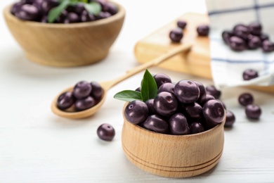Photo of Tasty acai berries in bowl on white wooden table, closeup