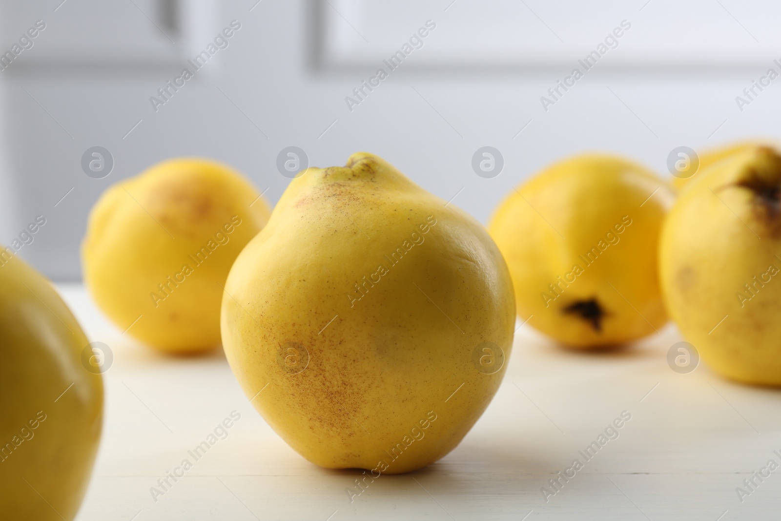 Photo of Tasty ripe quinces on white wooden table, closeup