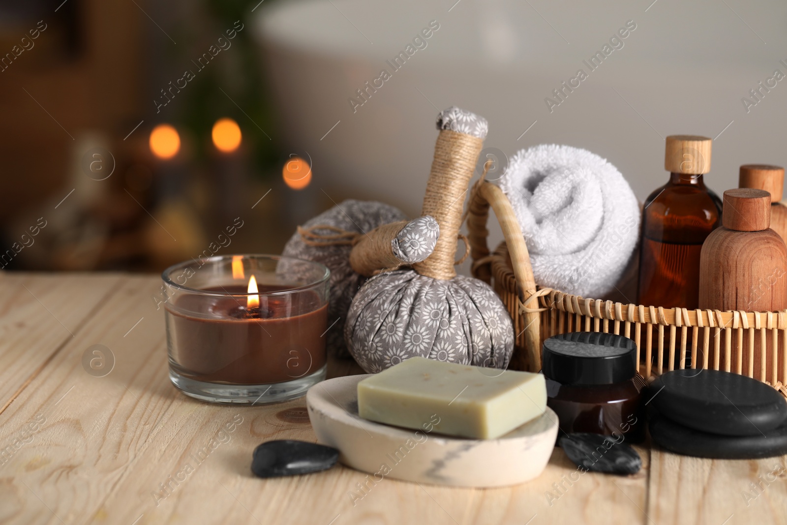 Photo of Composition with spa products and burning candle on wooden table in bathroom, closeup. Space for text