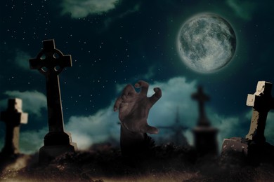 Image of Scary zombie rising out of grave at misty cemetery under full moon. Halloween monster