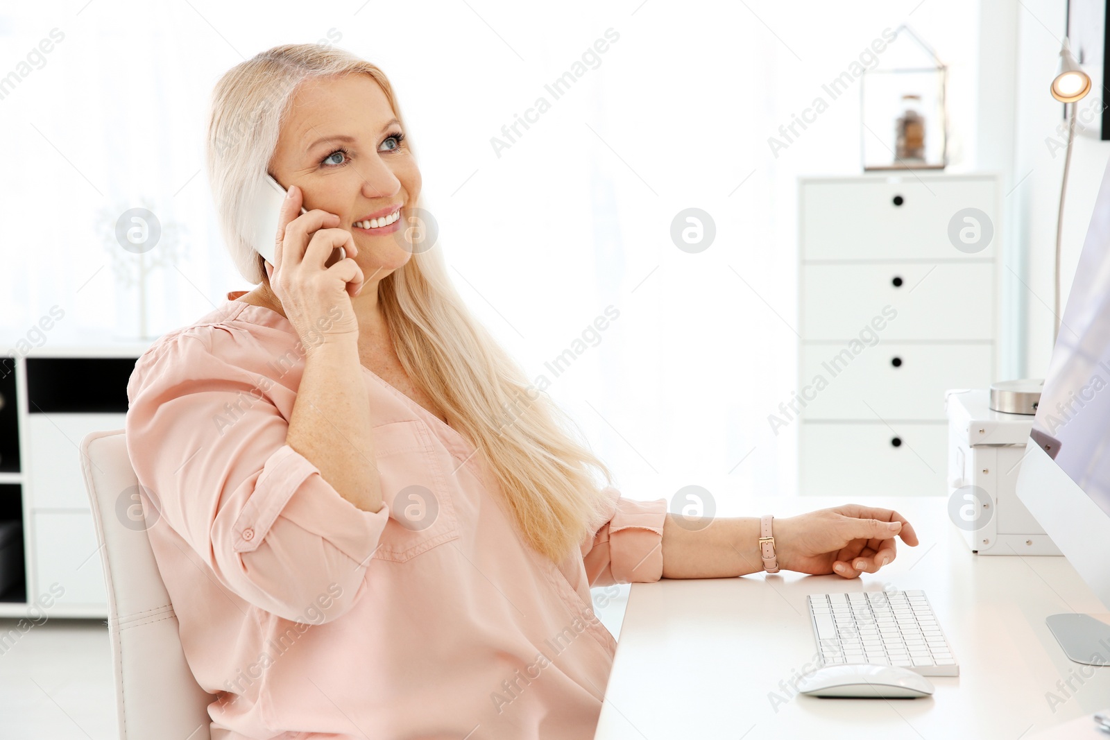 Photo of Mature woman talking on mobile phone at workplace