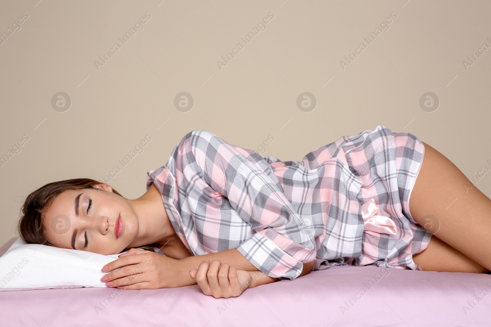 Photo of Beautiful teen girl sleeping with orthopedic pillow on bed against color background