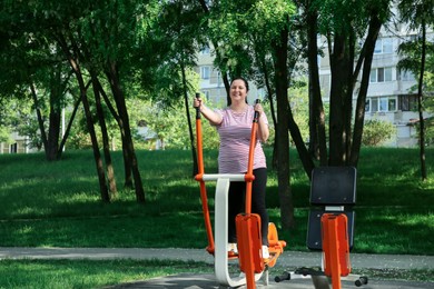 Overweight woman doing exercise with air walker in park