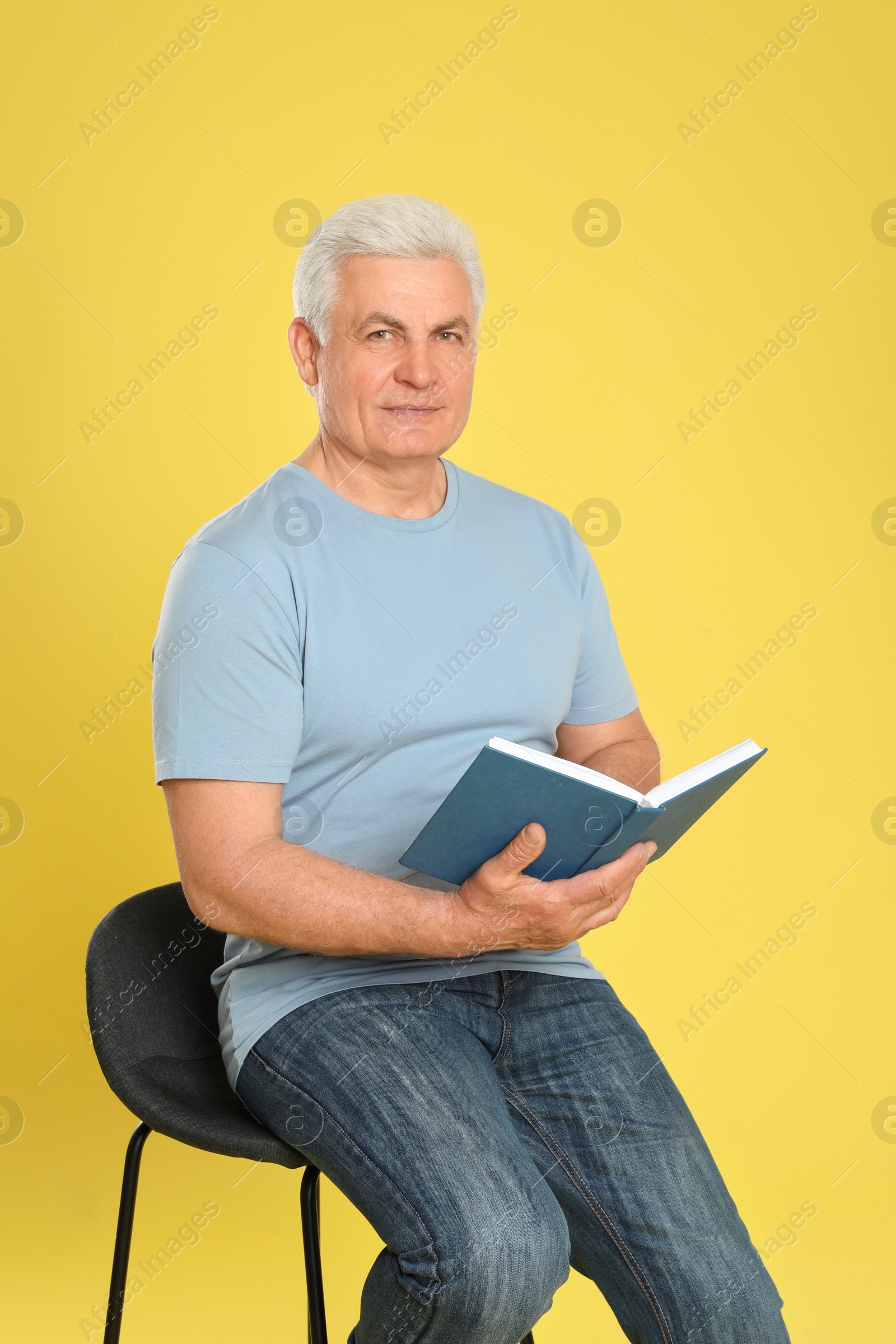 Photo of Senior man reading book on color background