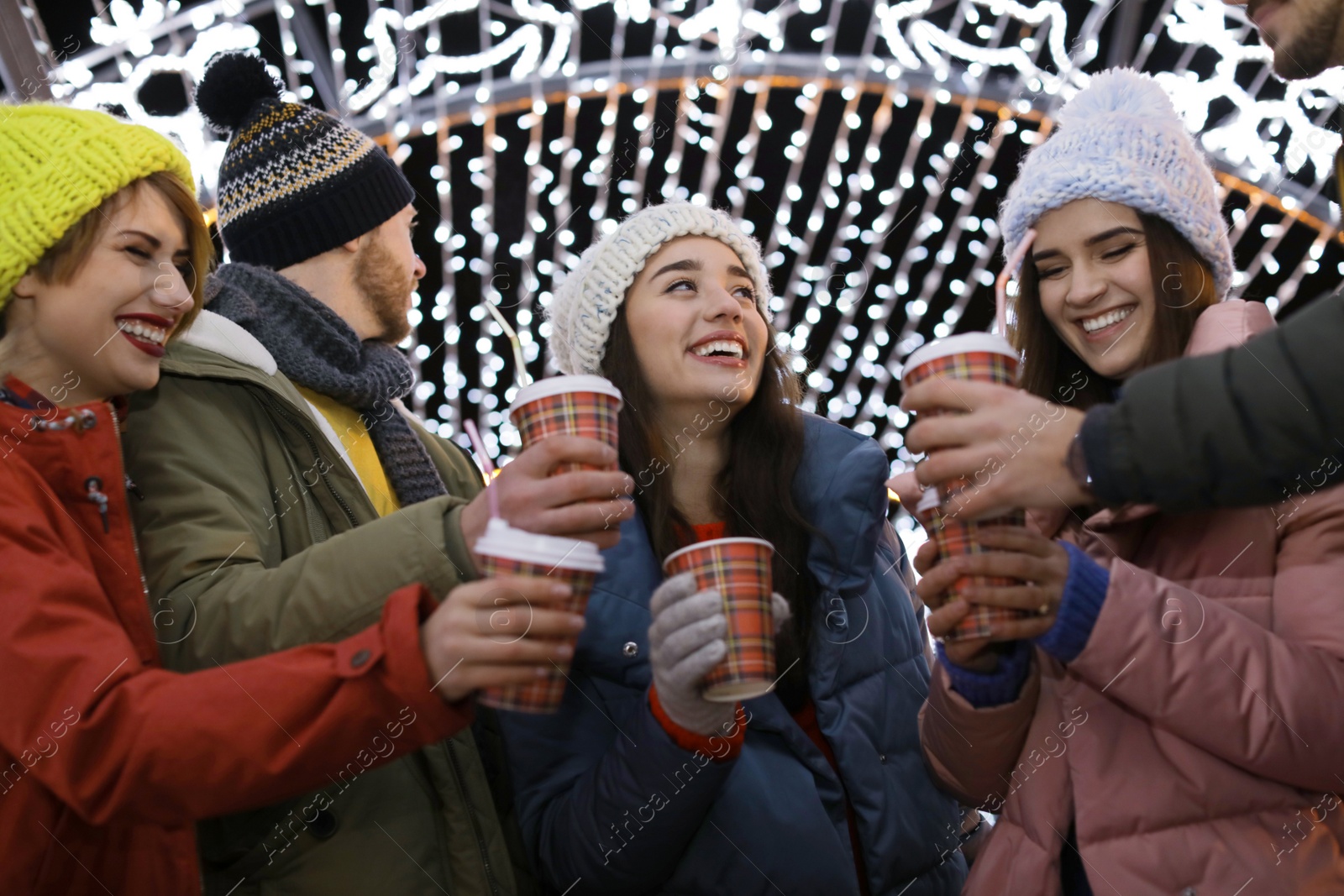 Photo of Happy friends with cups of mulled wine at winter fair