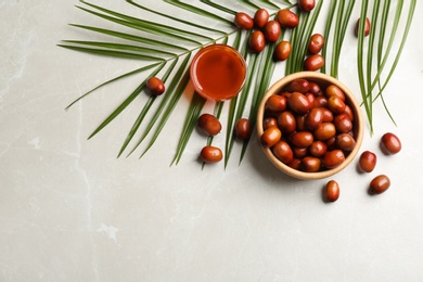 Palm fruits and oil on light marble table, flat lay. Space for text