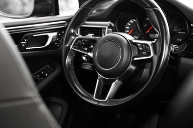 Photo of Steering wheel inside of modern black car, closeup