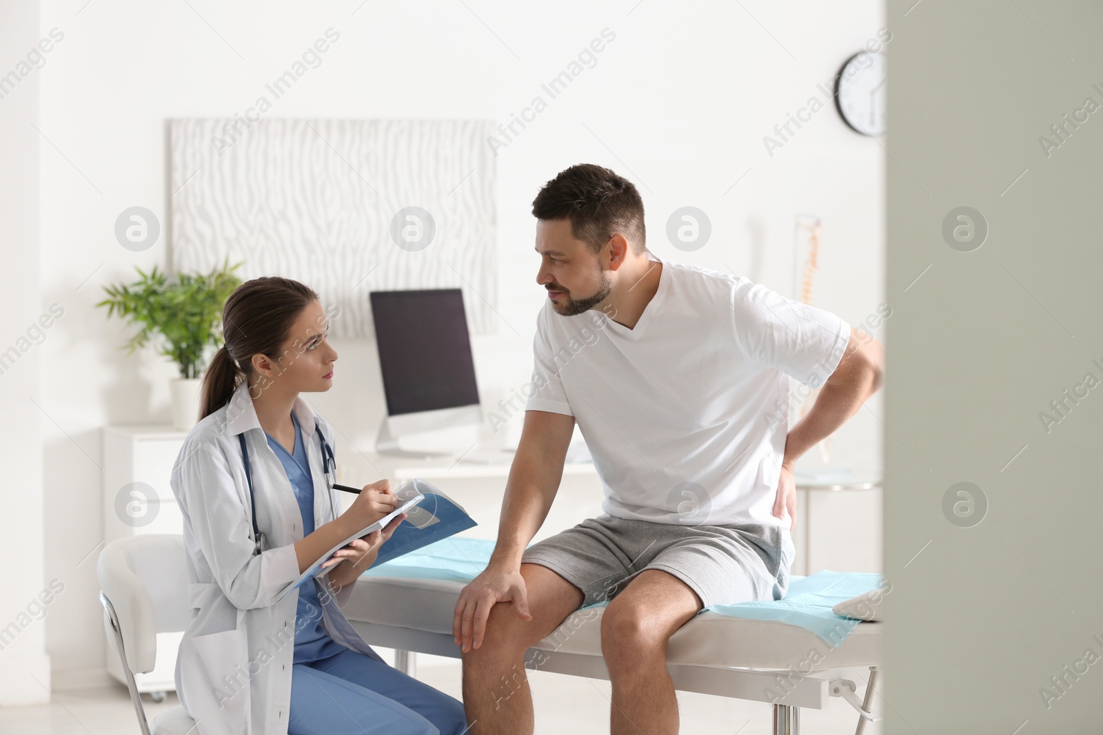 Photo of Female orthopedist examining patient with injured back in clinic