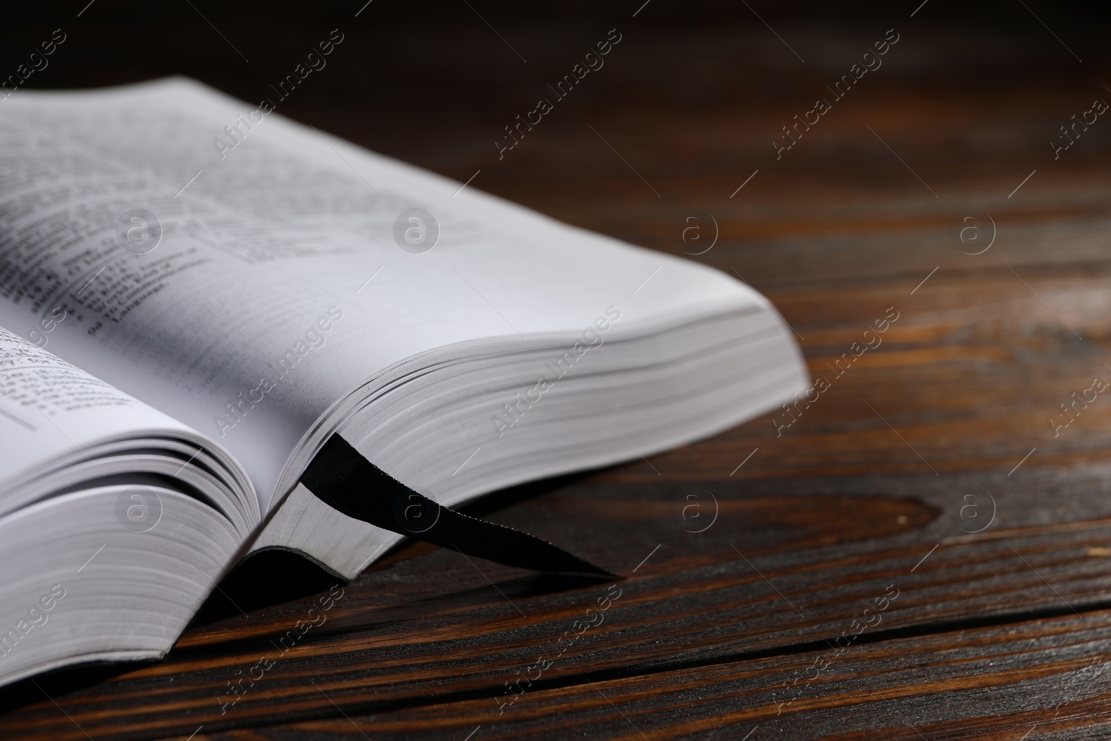 Photo of Open Bible on wooden table, closeup. Christian religious book