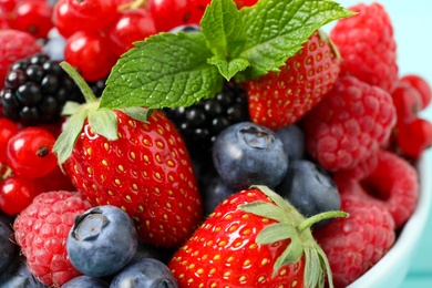 Photo of Mix of different fresh berries and mint in bowl, closeup