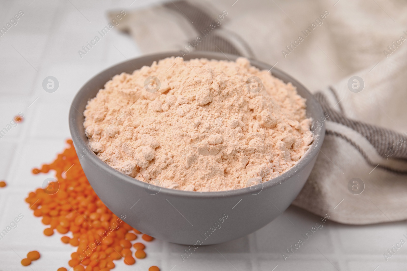 Photo of Bowl of lentil flour and seeds on white table, closeup