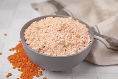 Bowl of lentil flour and seeds on white table, closeup